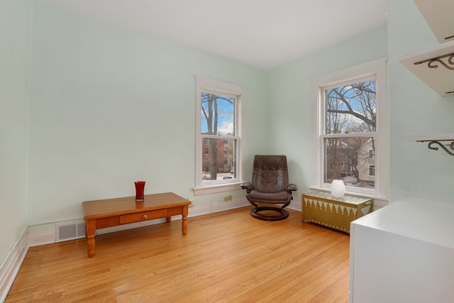 sitting room featuring light wood-style floors, visible vents, plenty of natural light, and baseboards