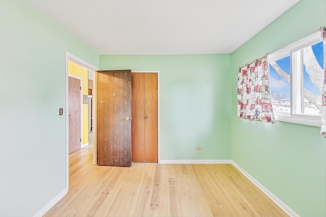 unfurnished bedroom featuring a closet, wood finished floors, and baseboards