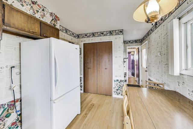 kitchen with plenty of natural light, light wood-style flooring, wallpapered walls, and freestanding refrigerator