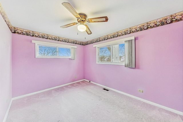 empty room with ceiling fan, carpet floors, visible vents, and baseboards