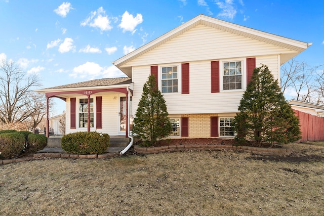 tri-level home with fence and brick siding