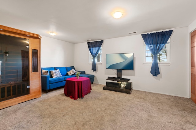 carpeted living room featuring visible vents, a healthy amount of sunlight, and baseboards