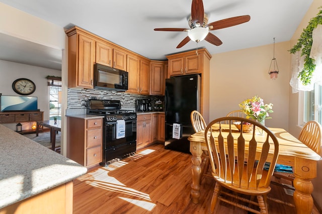 kitchen with black appliances, light wood-style flooring, light countertops, and tasteful backsplash