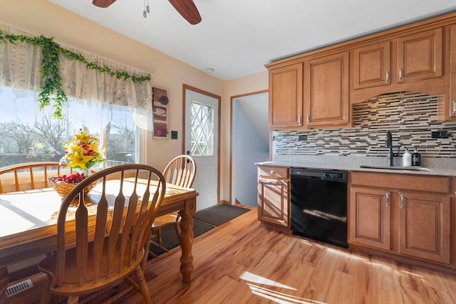 kitchen featuring light wood finished floors, decorative backsplash, dishwasher, and a sink