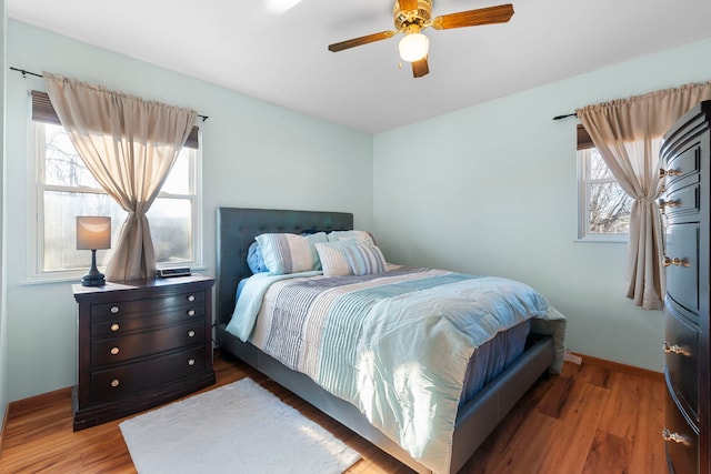 bedroom featuring baseboards, multiple windows, and wood finished floors