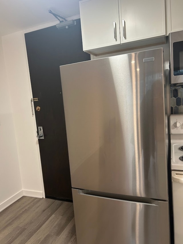 kitchen with tasteful backsplash, stainless steel appliances, white cabinetry, and hardwood / wood-style floors