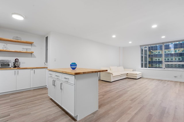 kitchen with a kitchen island, light wood-type flooring, butcher block counters, and white cabinets