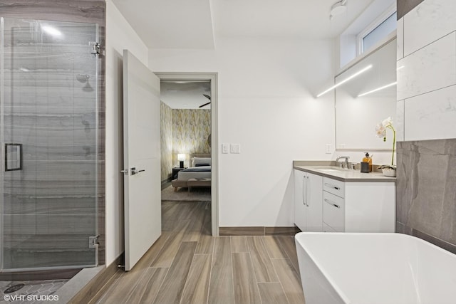 bathroom featuring wood finish floors, a soaking tub, vanity, ensuite bath, and a shower stall