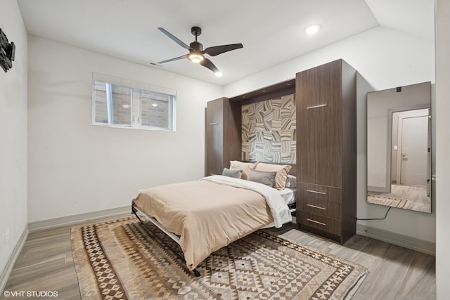 bedroom featuring lofted ceiling, visible vents, light wood-style floors, a ceiling fan, and baseboards