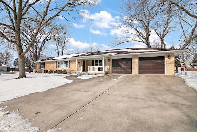 ranch-style house featuring a garage, concrete driveway, brick siding, and covered porch