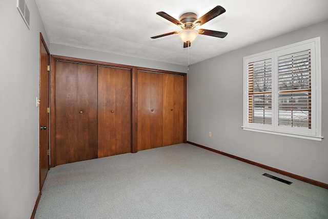 unfurnished bedroom featuring light carpet, baseboards, visible vents, and multiple closets