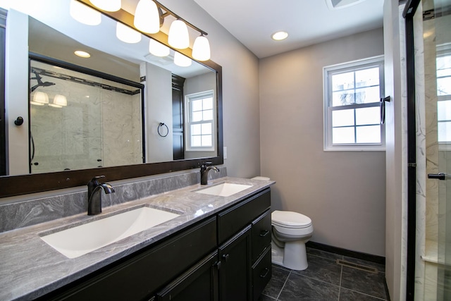 bathroom with double vanity, a stall shower, toilet, and a sink