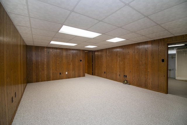 finished below grade area featuring carpet, wood walls, and a paneled ceiling