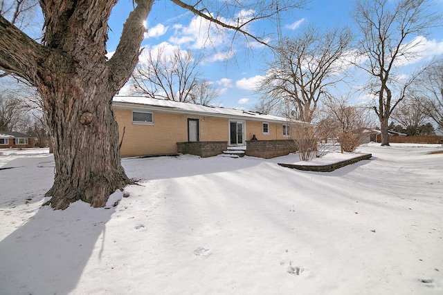 snow covered house featuring brick siding