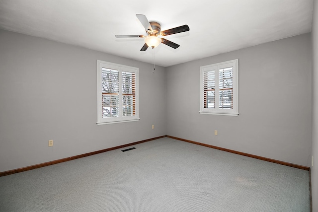 empty room with carpet flooring, visible vents, ceiling fan, and baseboards