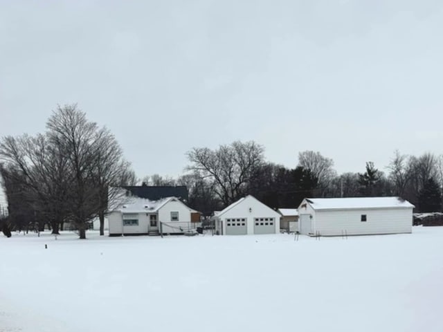 yard layered in snow with an outbuilding and a garage