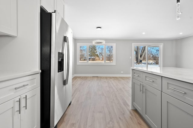 kitchen featuring baseboards, light wood-style flooring, decorative light fixtures, light stone countertops, and stainless steel refrigerator with ice dispenser