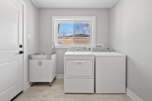 laundry room with cabinet space, baseboards, a sink, and washing machine and clothes dryer