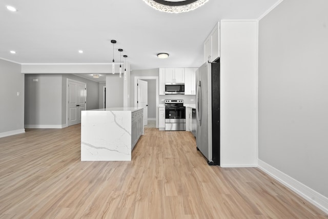 kitchen with white cabinets, a kitchen island, appliances with stainless steel finishes, light stone counters, and pendant lighting