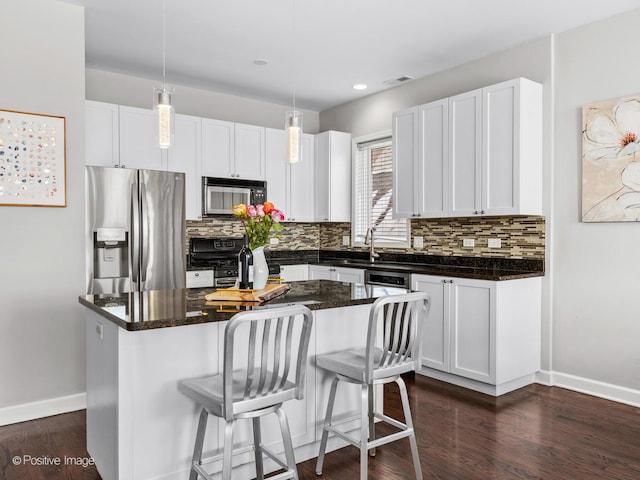 kitchen featuring white cabinets, a center island, stainless steel appliances, and decorative light fixtures