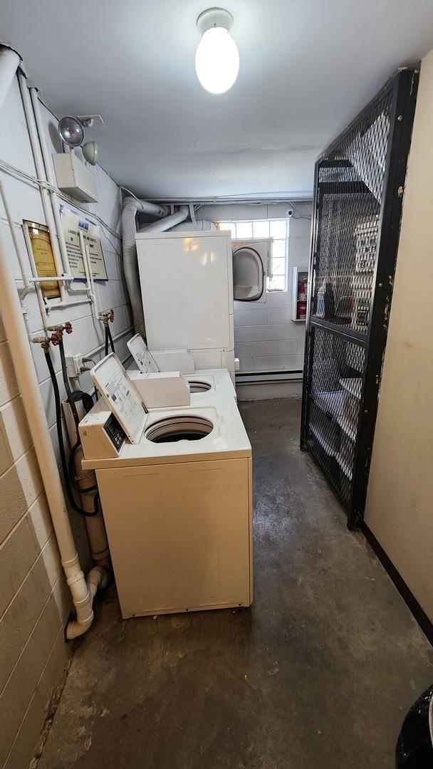 clothes washing area featuring concrete block wall and washing machine and dryer