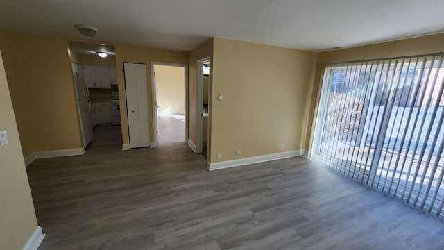 empty room featuring wood finished floors, visible vents, and baseboards