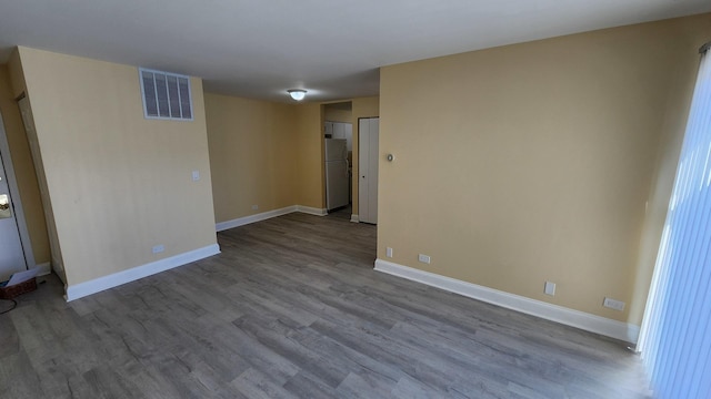 empty room featuring light wood-style floors, baseboards, and visible vents