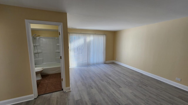 unfurnished bedroom featuring light wood-style floors, ensuite bath, and baseboards