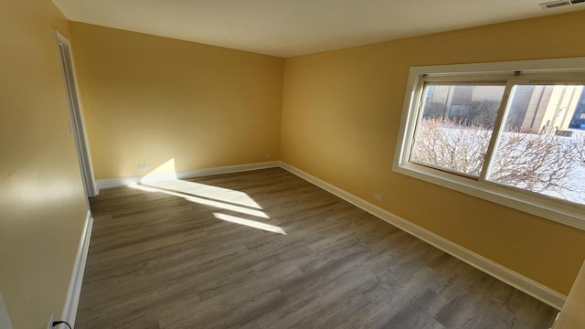 empty room featuring visible vents, baseboards, and wood finished floors