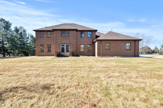 rear view of house featuring a lawn and brick siding