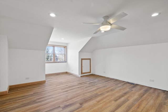 additional living space featuring vaulted ceiling, light wood finished floors, a ceiling fan, and baseboards