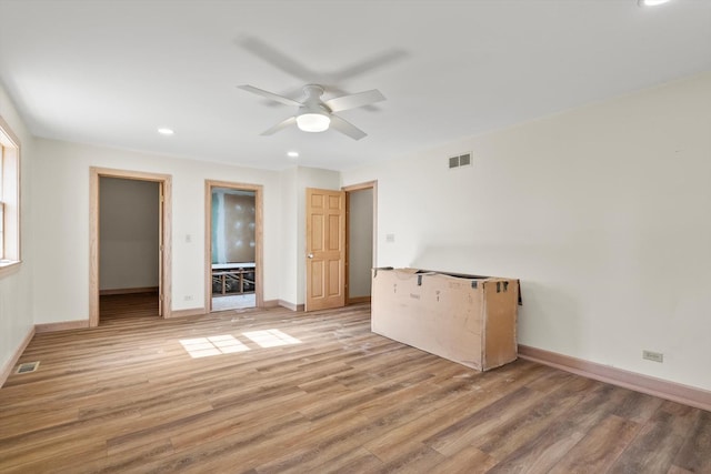 empty room with wood finished floors, visible vents, and baseboards