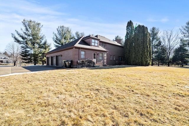 view of front of house featuring a garage, a front yard, aphalt driveway, and brick siding