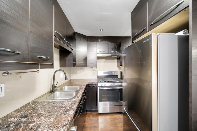 kitchen featuring dark wood-style floors, dark stone countertops, stainless steel appliances, under cabinet range hood, and a sink