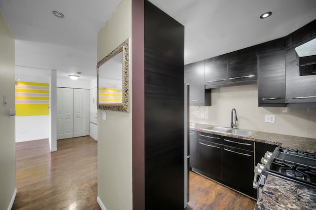 kitchen featuring recessed lighting, dark cabinets, dark wood-style flooring, a sink, and range with gas cooktop