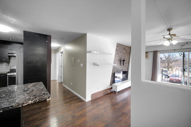 kitchen featuring dark wood-style flooring, a fireplace, baseboards, stainless steel gas range, and modern cabinets