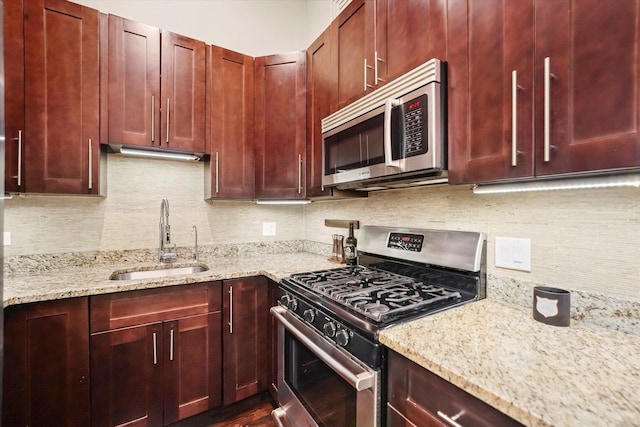 kitchen with appliances with stainless steel finishes, sink, backsplash, and light stone counters