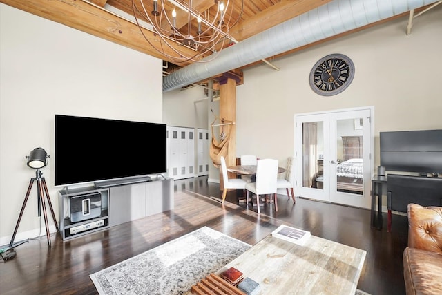 living room featuring an inviting chandelier, dark wood-type flooring, french doors, a high ceiling, and beam ceiling