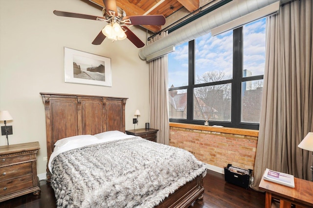 bedroom featuring ceiling fan, dark wood-type flooring, and brick wall