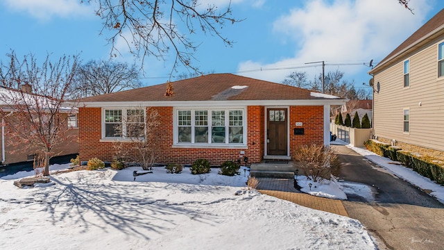 bungalow-style home with driveway and brick siding