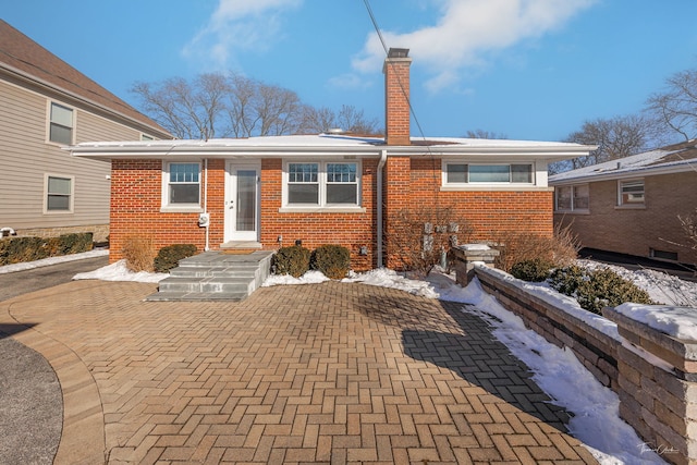 view of front facade featuring a chimney and brick siding