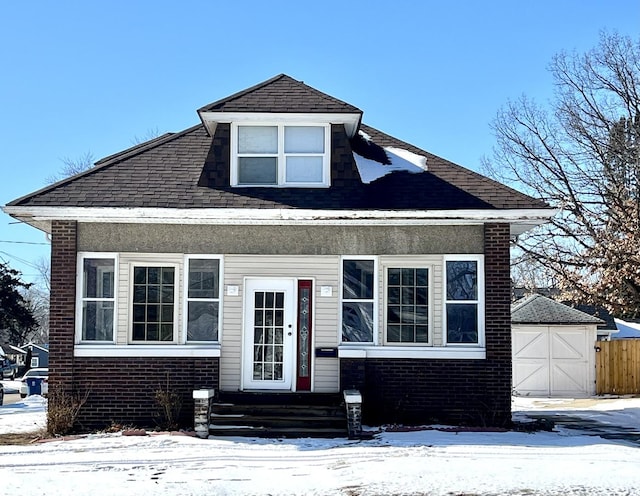 bungalow-style home featuring a garage, brick siding, roof with shingles, and entry steps