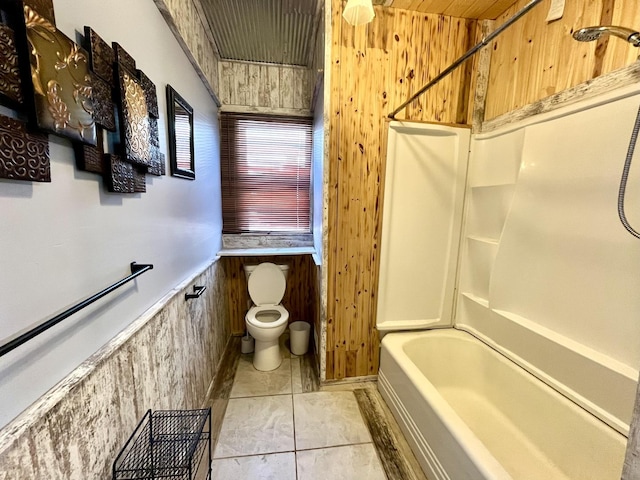 full bath with toilet, washtub / shower combination, wainscoting, wooden walls, and tile patterned flooring