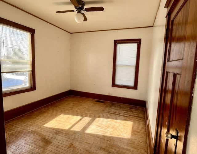 spare room with visible vents, baseboards, a ceiling fan, light wood-style flooring, and crown molding