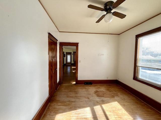 unfurnished room with ornamental molding, light wood-type flooring, and baseboards