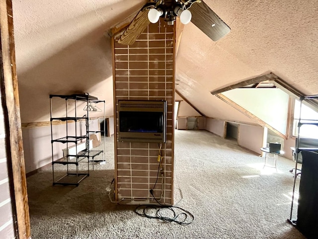 additional living space with ceiling fan, heating unit, vaulted ceiling, a textured ceiling, and carpet flooring