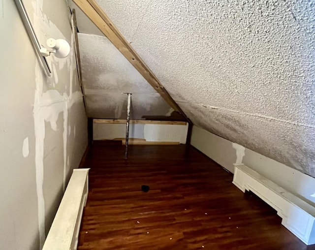 bonus room with lofted ceiling and dark wood-style flooring