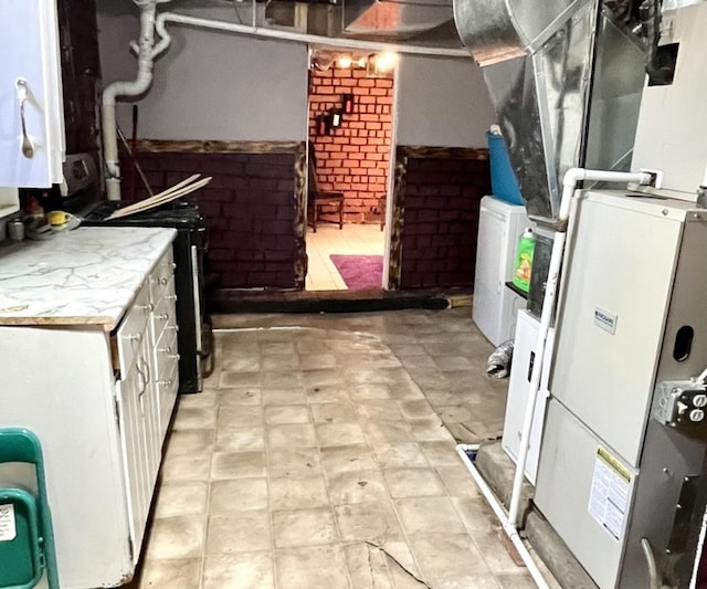 kitchen with light countertops, washer / dryer, white cabinetry, and heating unit