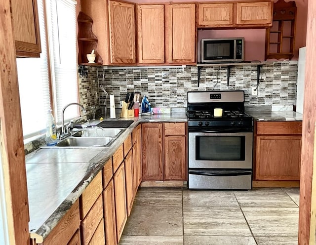 kitchen featuring stainless steel appliances, brown cabinetry, dark countertops, and a sink