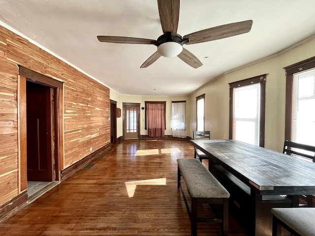 unfurnished dining area with a ceiling fan, dark wood-style flooring, and ornamental molding